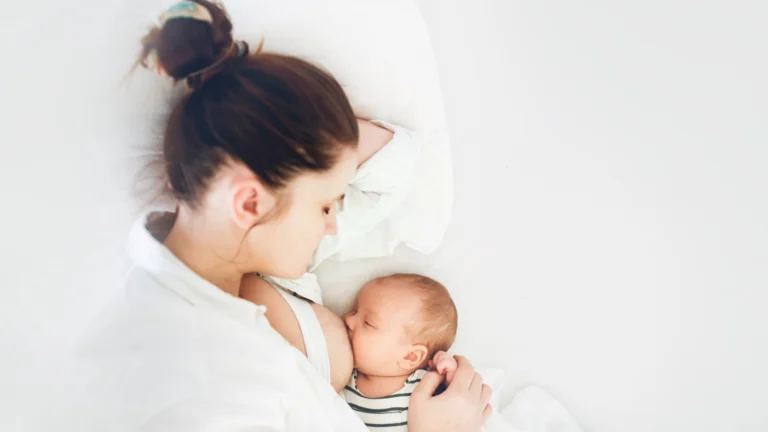 mom and newborn baby, mother breastfeeds the baby lying on a white background on the bed