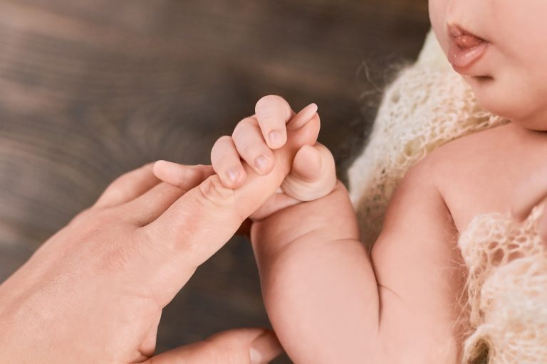 Infant holding female finger